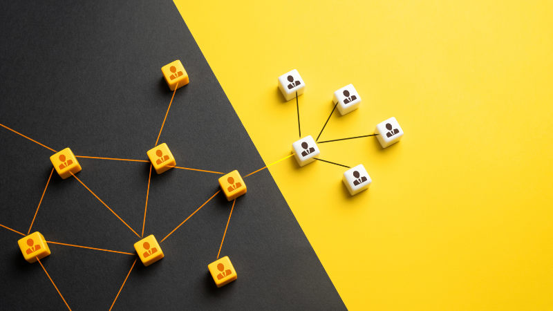 A conceptual illustration of interconnected blocks with person icons, divided between a black and yellow background. The design symbolizes collaboration and the delegation of tasks, representing business process outsourcing and its role in streamlining operations.