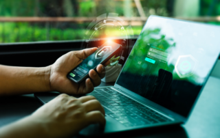 A person using a smartphone and laptop with glowing security icons on both screens, symbolizing secure access and data protection. The image highlights the importance of robust Cybersecurity measures to safeguard sensitive information in a connected digital environment.